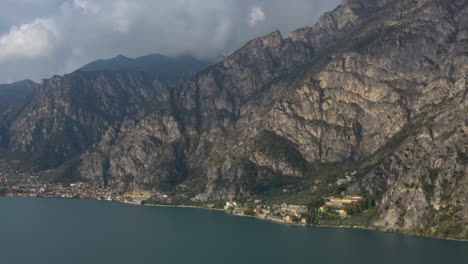 dolly in aerial shot flying towards a dramatic, moody mountainous landscape near lake garda