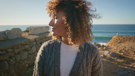 tender brunette posing sea cliff enjoying nature portrait. curly woman relaxing