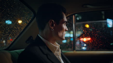 hombre serio mirando por la ventana del coche por la noche de cerca. elegante gerente de la ciudad
