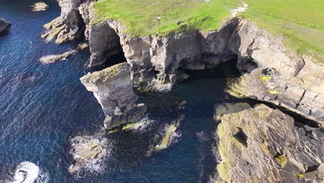 vista aérea de aves volando sobre el mar y la pintoresca costa de escocia en un día soleado, tomada por un dron