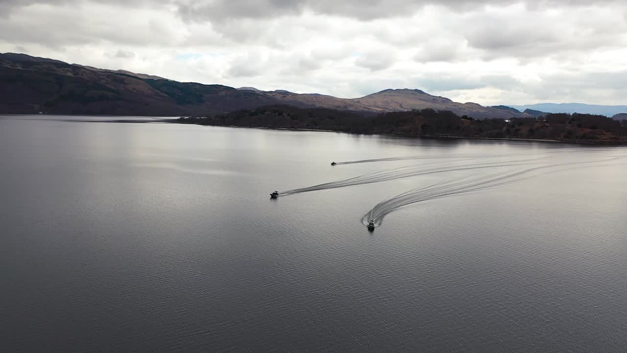 이른 봄에 loch lomond에서 순항하는 3척의 보트의 영화 같은 공중 슬로우 모션 높음에서 낮은 드론 각도