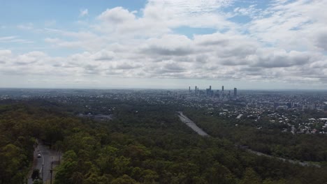 Drone-Volando-Sobre-Una-Montaña-Con-Una-Gran-Ciudad-En-El-Fondo