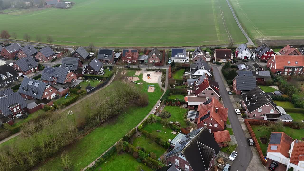 Aerial flyover housing area with playground near rural farm fields at foggy day. American suburb district of town. Solar panels on roof of building. Sustainable energy theme. Winter season in USA.