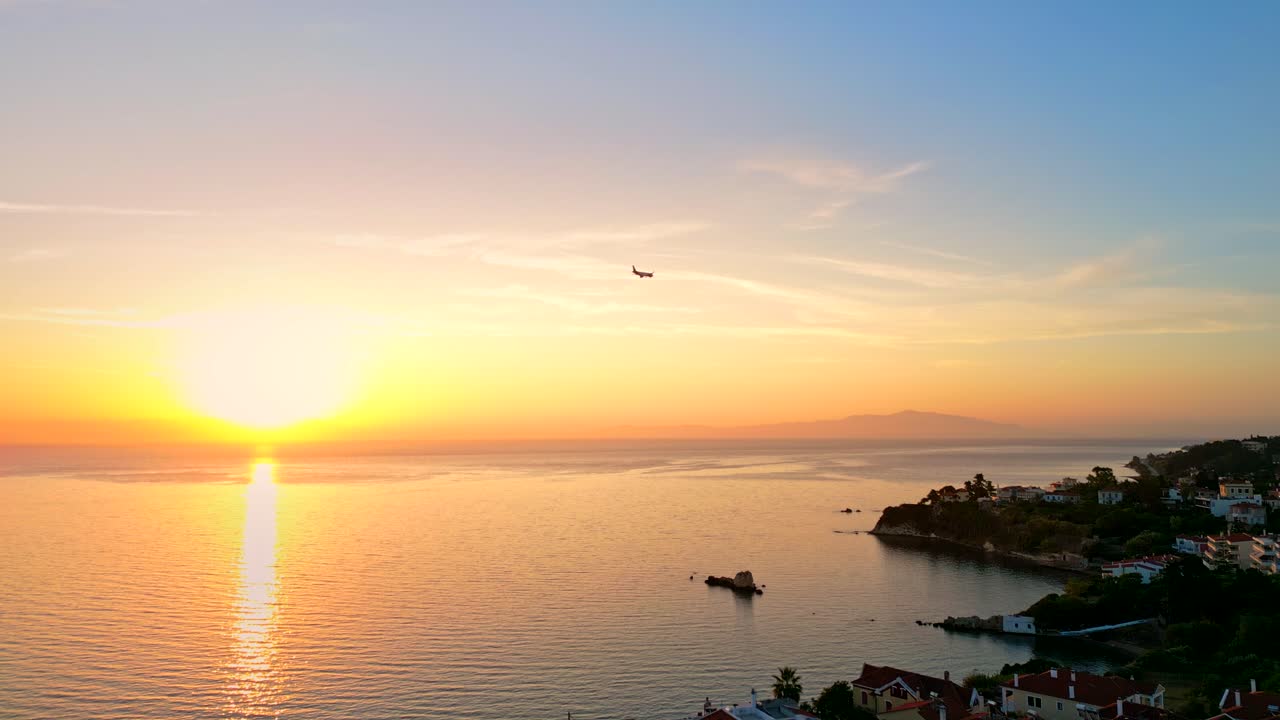A plane flying by, while the sun sets on the horizon in Greece