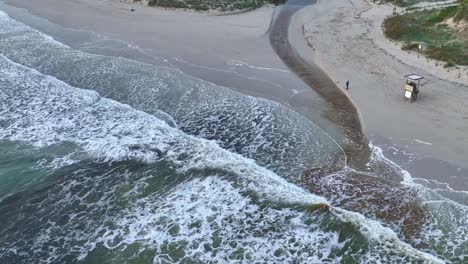son boy beach in menorca, spain with waves hitting the coastline slowly