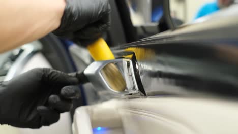car wash worker washing a car car service concept. a car wash worker cleans the wheels of a car, wearing a bright yellow waterproof uniform in a service garage