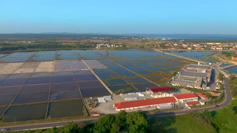 Luftaufnahme-Mehrerer-Landwirtschaftlicher-Felder-Mit-Wasserstand,-Die-An-Große-Lagerhäuser-Mit-Roten-Dächern-Angrenzen