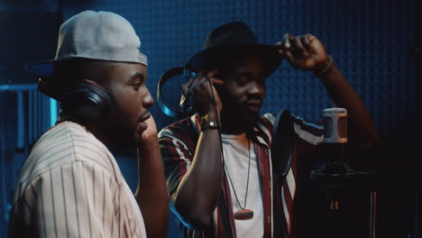 Close-Up-Of-The-Young-Male-Duo-Recording-A-Song-Hit-In-The-Dark-Sound-Studio-And-Singing-In-The-Microphone