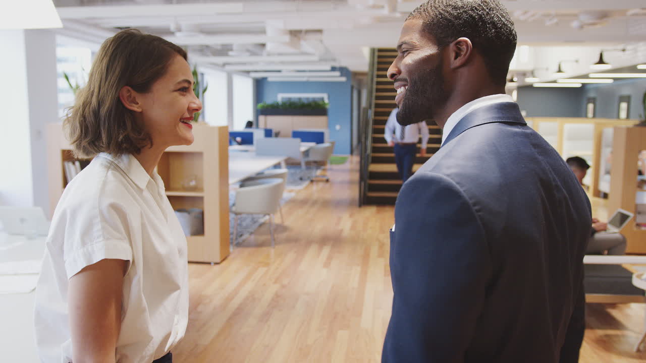 Two Businesswoman And Businessman Meet And Shake Hands In Modern Open Plan Office