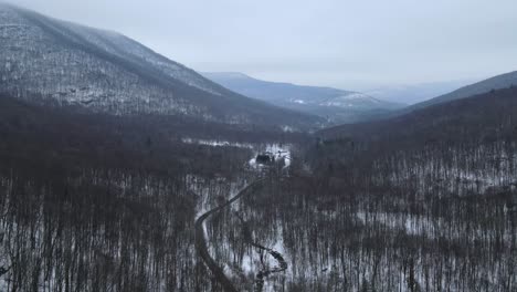 flying over a snowy, beautiful mountain valley with a remote road below