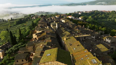 fly over the historical hill town of san gimignano at the early misty morning in tuscany, italy