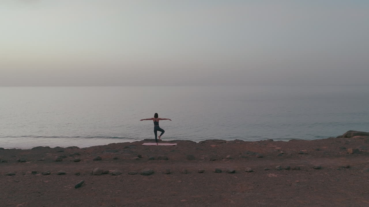 해가 뜨는 해변에서 요가를 연습하는 여자