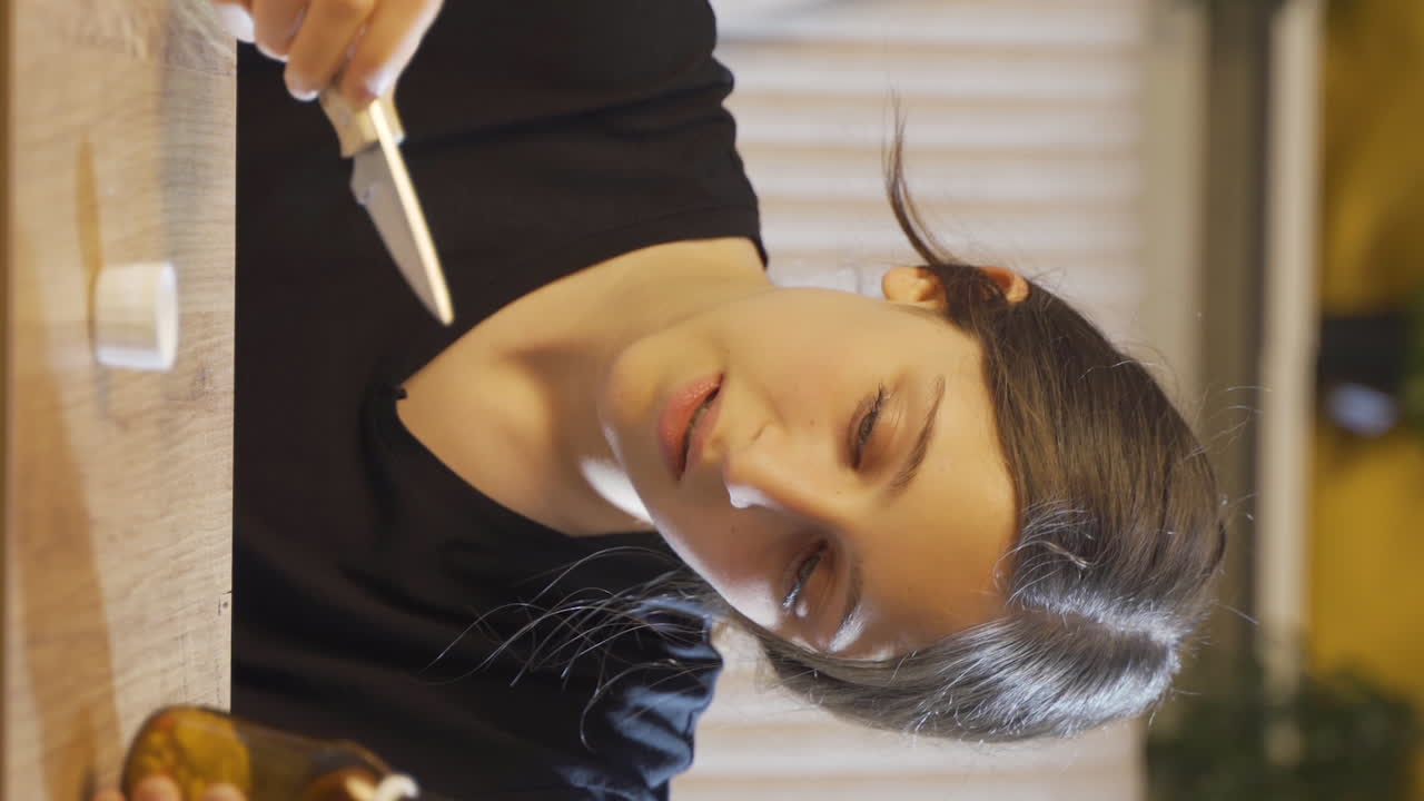 문제가 있는 젊은 여성의 수직 비디오가 그녀의 앞에 있는 칼과 약을 보고 있습니다.