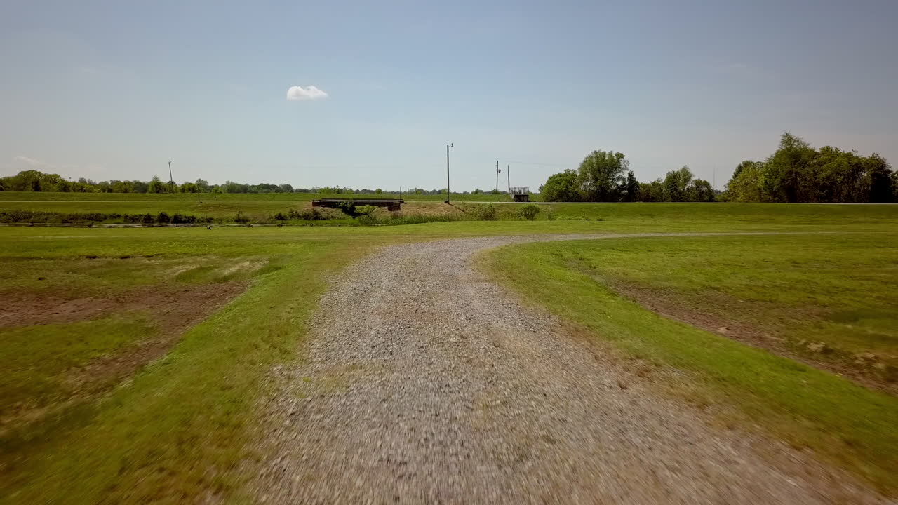 low flight over gravel road with green grass and blue sky