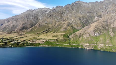 Mountain-Range-The-Remarkables-ond-lakefront-of-Lake-Wakatipu,-Queenstown,-New-Zealand---aerial