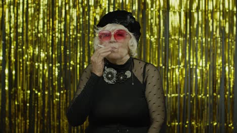 Elderly-style-mature-woman-in-fashion-black-clothes-in-sunglasses-posing,-smoke-cigarette