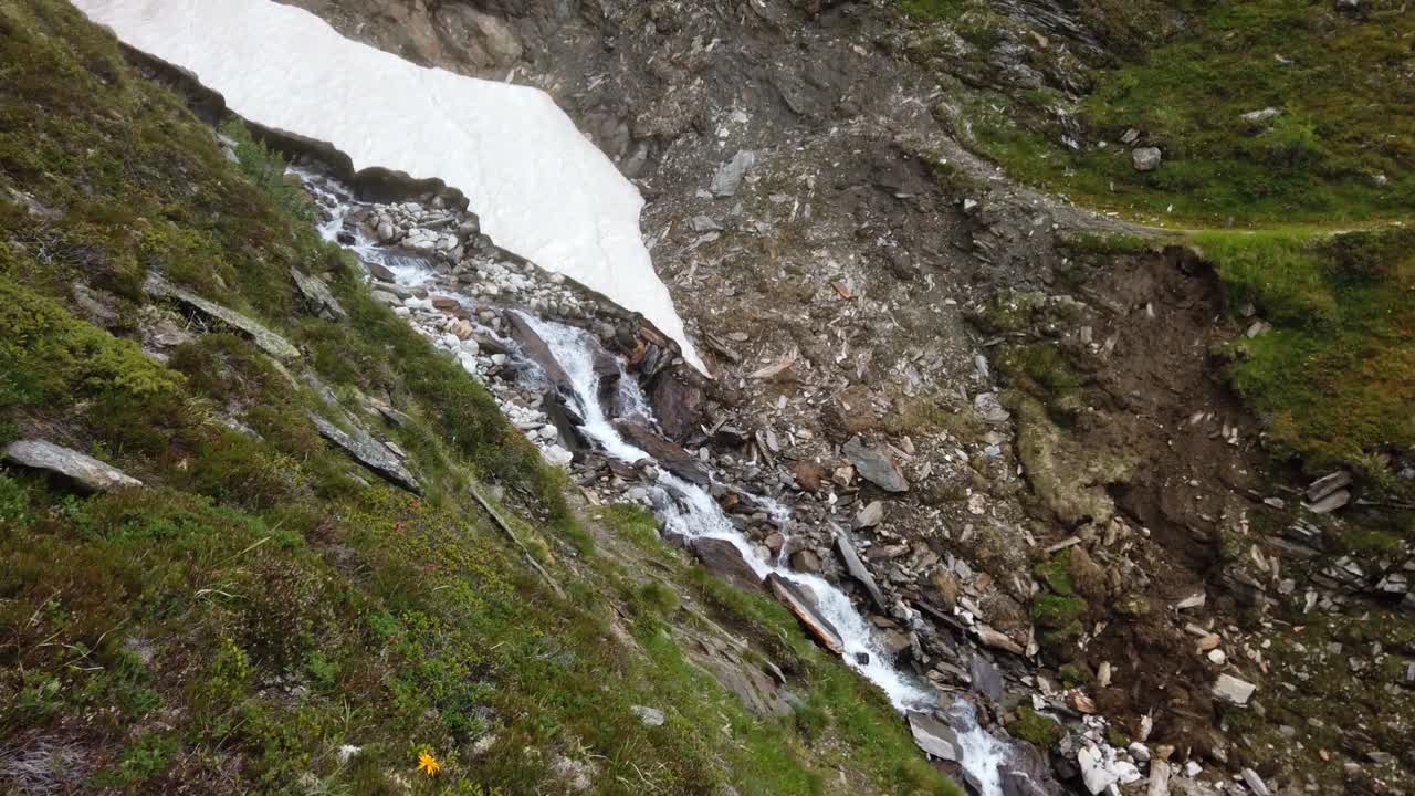Vista statica di una cascata alpina impetuosa in un aspro e ripido terreno montuoso.