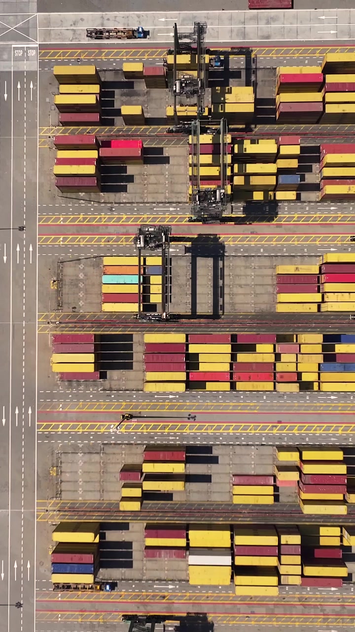 Luftperspektiv af en travl containerterminal, der viser talrige shippingcontainere og fragtaktivitet. Stedet omfatter betydelige fragttransportoperationer for global handel.