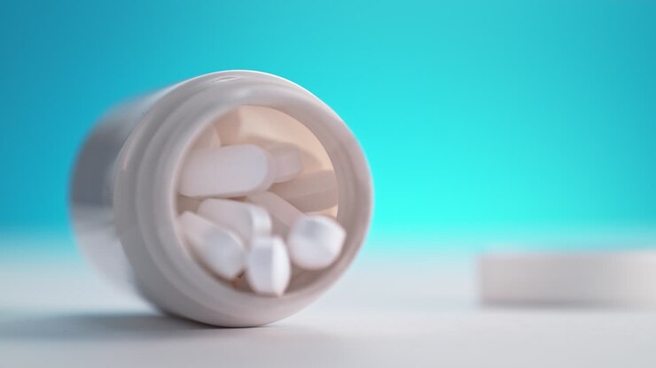 una botella de analgésicos cae sobre una mesa y las pastillas de paracetamol se derraman, dispersándose en macro y cámara lenta