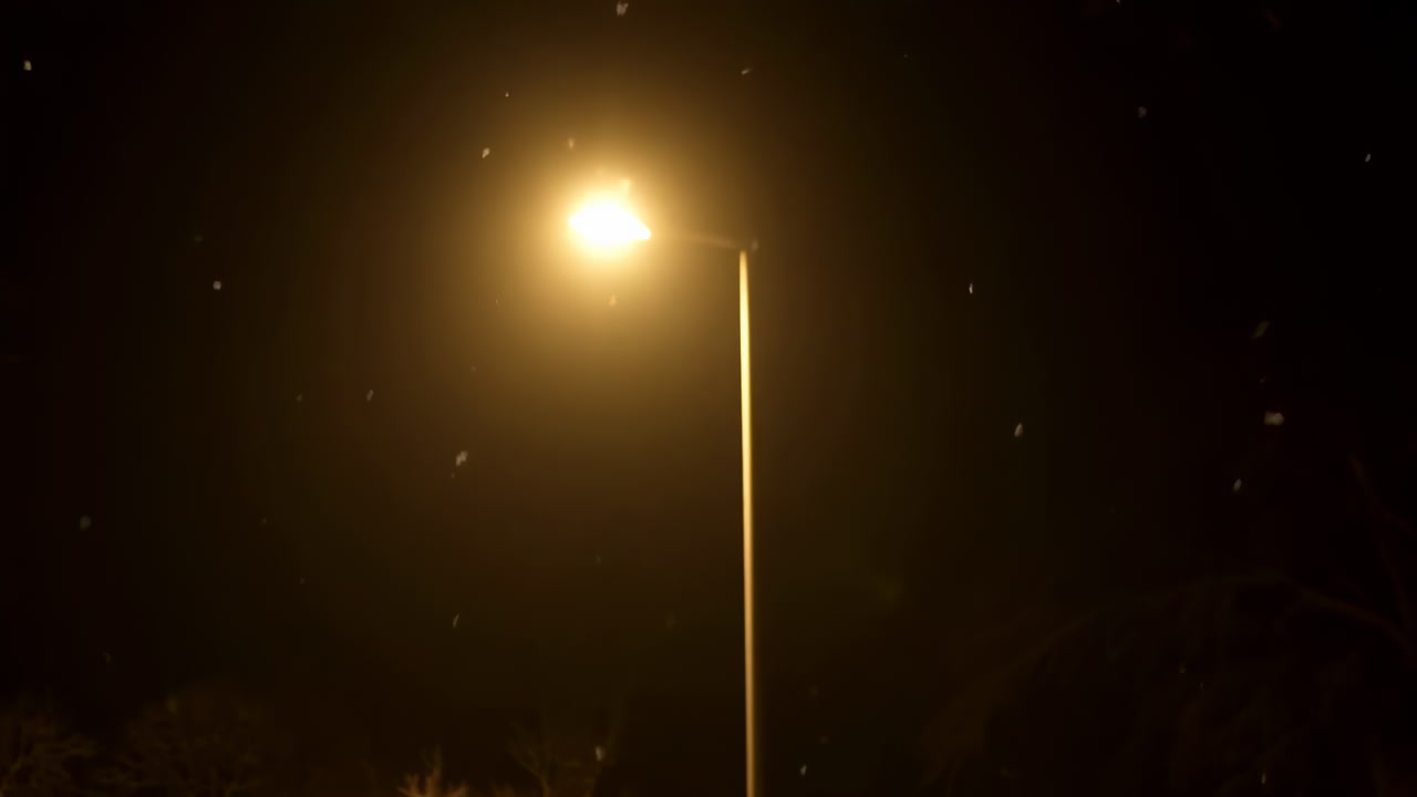 Lonely Lamppost Glowing In Snowfall, Moody Cinematic Night Scene With Warm Amber Sodium Glow, Drifting