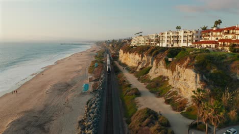 vista aérea siguiendo detrás de un tren amtrak a lo largo de la costa en san clemente, california