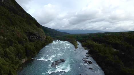 Dolly-out-aerial-view-of-the-Petrohue-River-with-cloudy-mountains-in-the-background,-southern-Chile