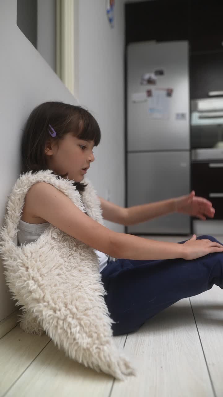 Young Girl Sitting on the Floor in a Kitchen
