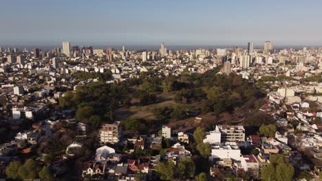 Toma-Aérea-Del-Idílico-Parque-Saavedra-Rodeado-De-Rascacielos-Gigantes-De-La-Ciudad-De-Buenos-Aires-Durante-La-Puesta-De-Sol