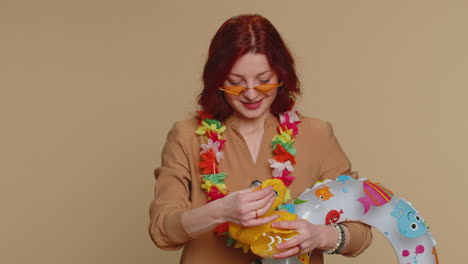 woman in sunglasses and a lei holding an inflatable duck and ring