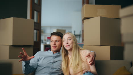 new owners sit down on couch between carton boxes close up. couple enjoy moving.