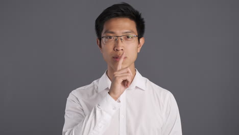 아시아인 남자가 카메라에 침 제스처를 하고 있습니다.