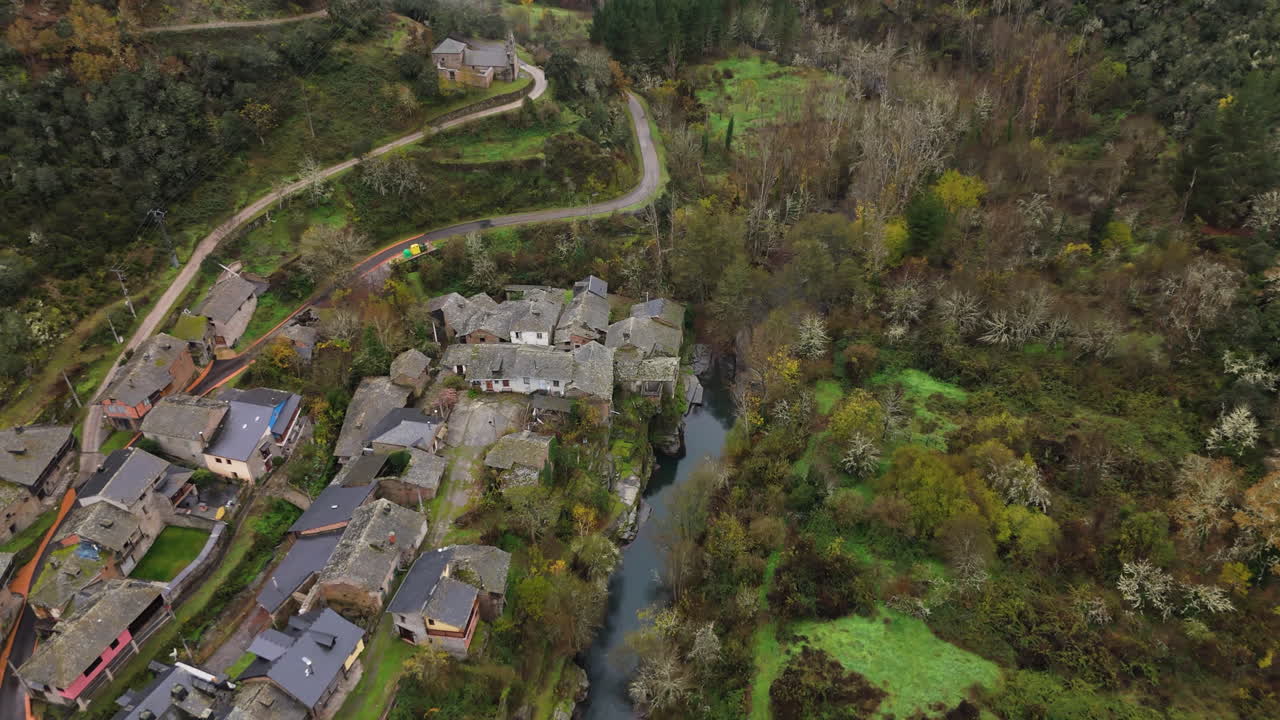 Drone flies over a medieval village surrounded by lush nature and a winding river in Northern Spain