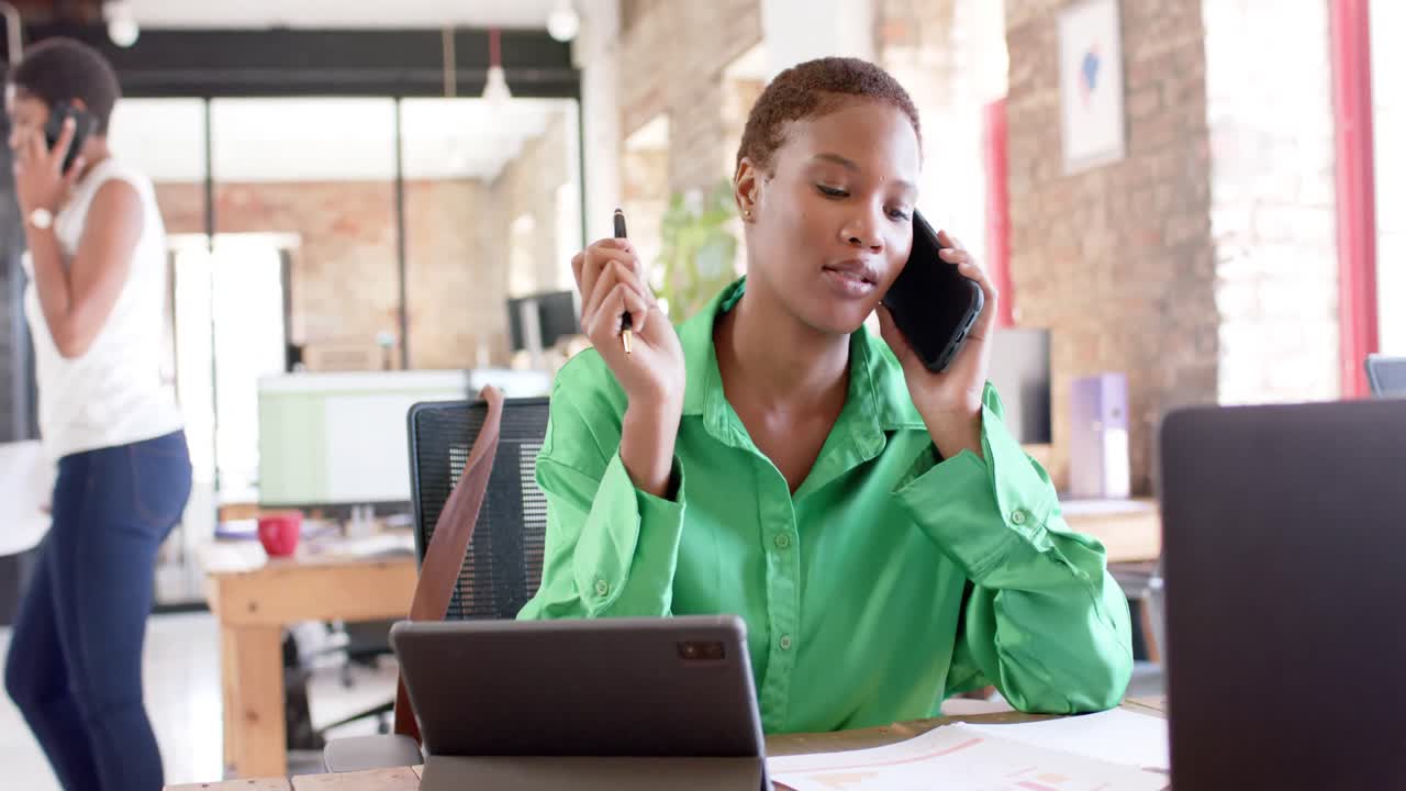 Happy african american casual businesswoman talking on smartphone in office in slow motion