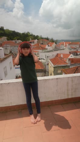 young girl with headphones on rooftop