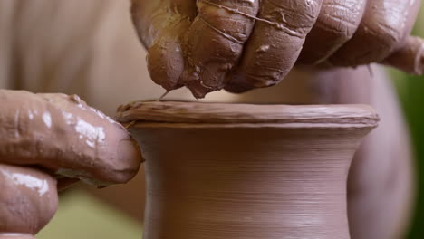 artisan craftsman slow motion trimming wet clay vessel neck with thread close up