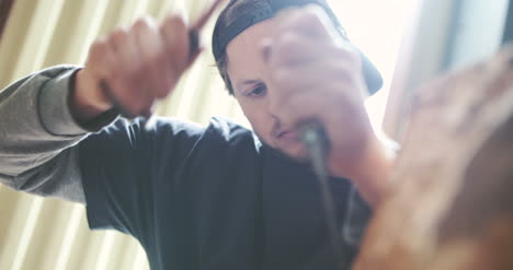 joven carpintero dando forma a la madera con cincel 4