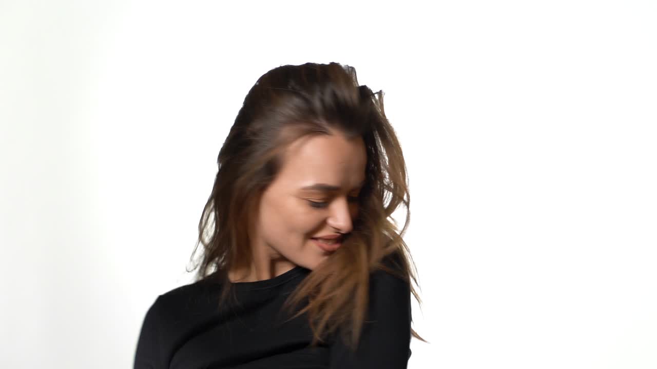 pretty woman with long hair is turning around and posing for the camera in the studio on a white background. Close-up