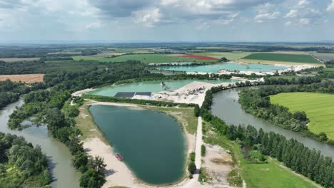 Aerial-descending-drone-footage-of-the-Small-Danube-river-capturing-gravel-pits-and-glistening-lakes
