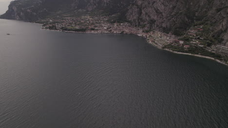 Droneshot-over-the-city-Limone-Italy-on-Lake-Garda-on-a-grey-day-with-mountains-clouds-and-water-LOG