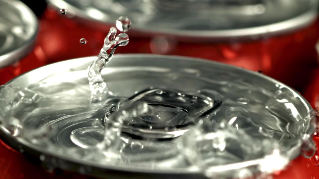 Gocce d'acqua che schizzano su una lattina di bibita rossa fredda al rallentatore