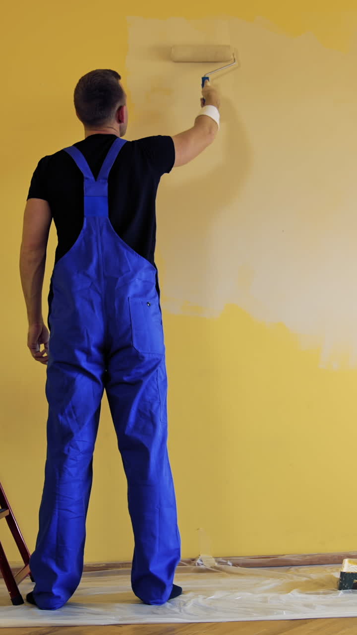 Painter paints on yellow wall. Repair, building and home concept. Vertical video