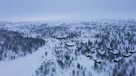 Aerial-view-circling-cabins-in-Kiilopaa,-gloomy-winter-day-in-Saariselka,-Finland