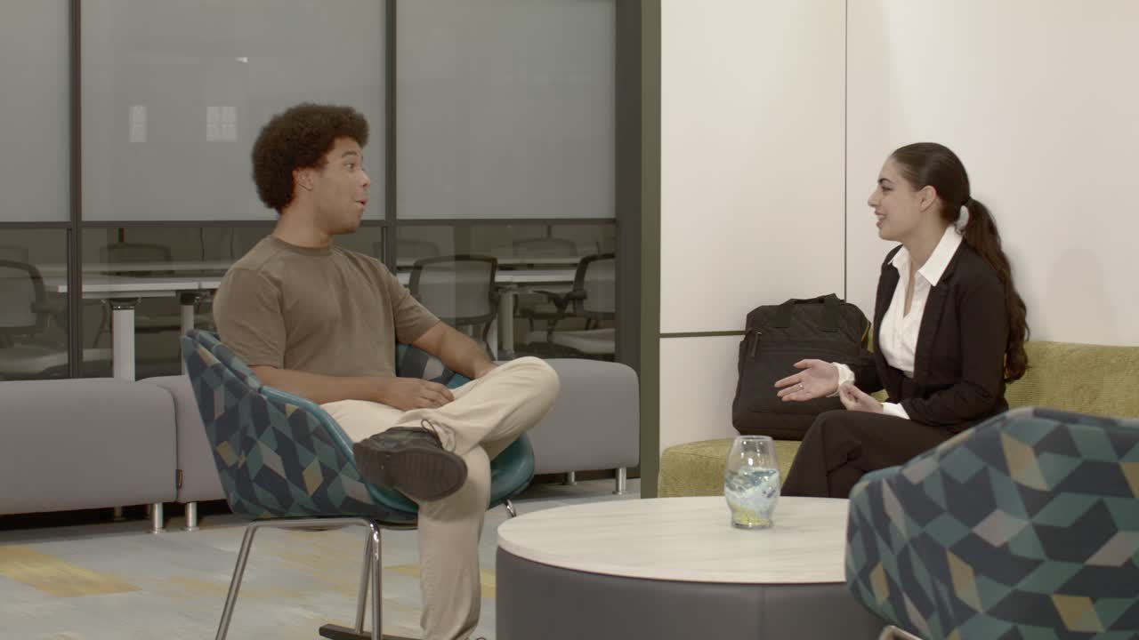 African American male in his 20's in an office setting talking to an Arab American female in her 20's with dolly video left to right wide shot