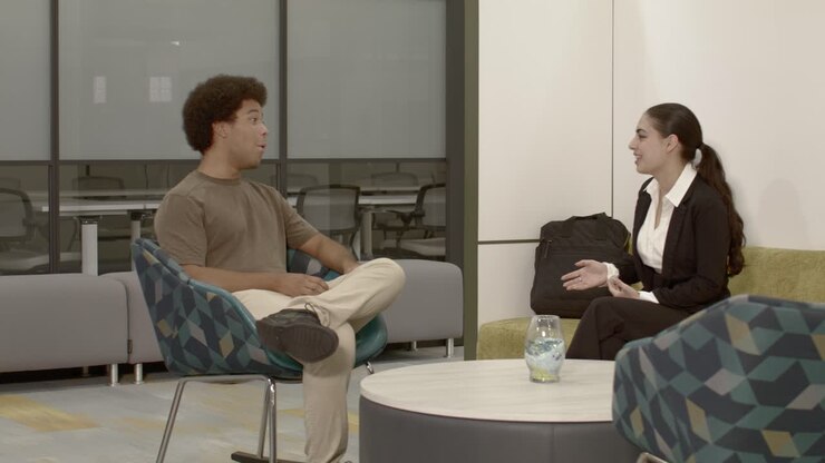 African American male in his 20's in an office setting talking to an Arab American female in her 20's with dolly video left to right wide shot