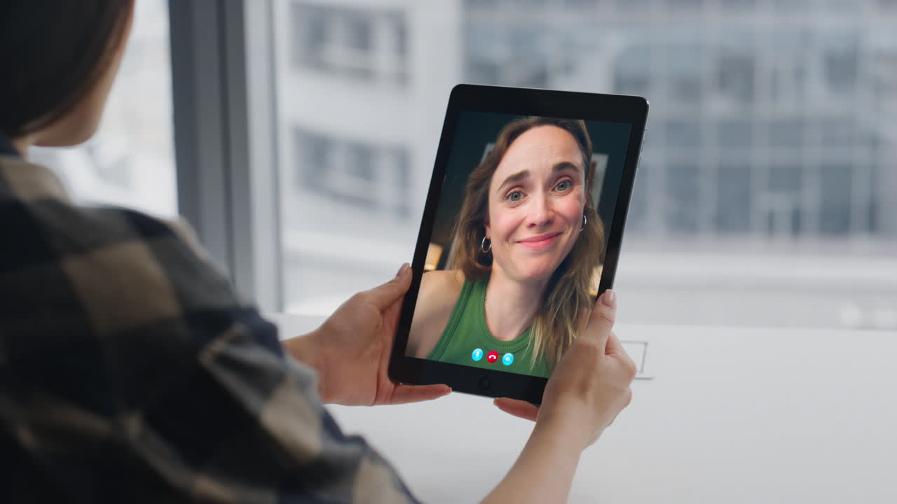 Primo piano di mani di donna che utilizzano un tablet per una conferenza virtuale con vista sulla città