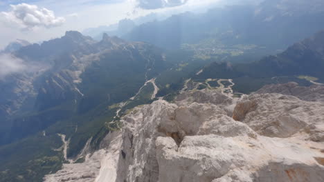 drone descending over rocky ridge of mountain peaks towards valley in summer season, dolomites in italy