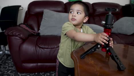 Un-Bebé-De-18-Meses-Jugando-Con-Un-Trípode-Para-Cámara-En-Casa