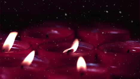 animación de nieve cayendo sobre velas rojas encendidas