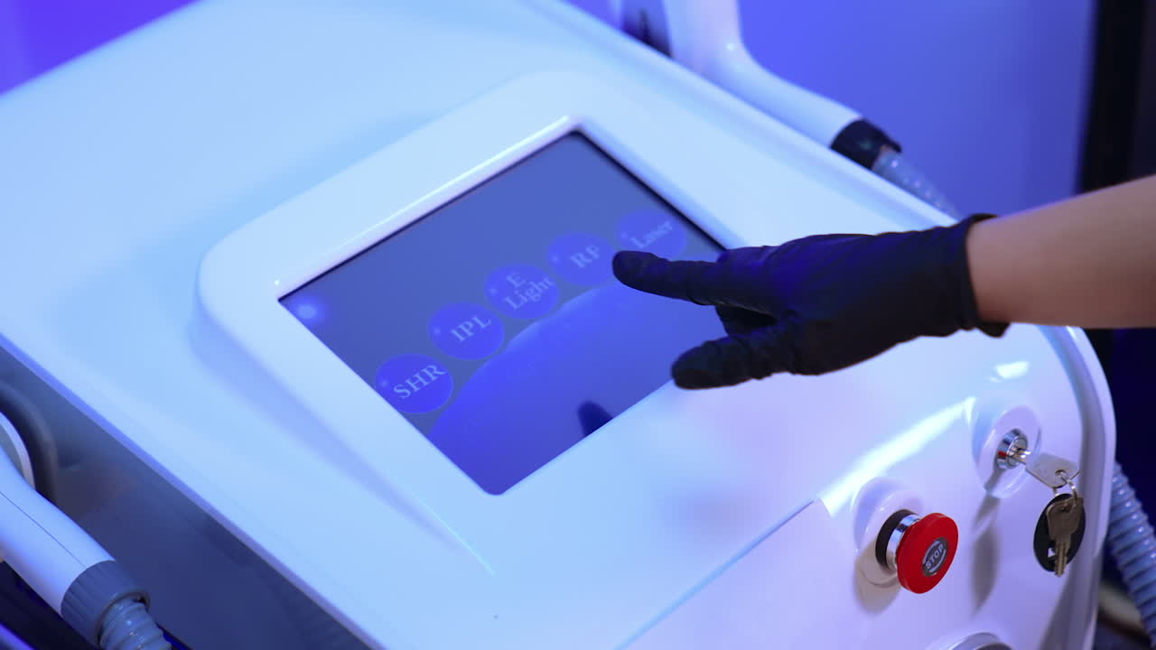 Gloved cosmetologist's hand chooses the necessary parameter on the sensor screen of equipment. Beautician prepares laser for usage.