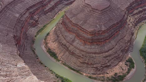 Excelente-Toma-Aérea-Del-Río-San-Juan-Curvándose-Alrededor-De-Una-Gran-Formación-Rocosa-En-Utah